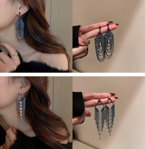 Detail of silver U-shaped earrings with rhinestones, tassels and blue crystal layers