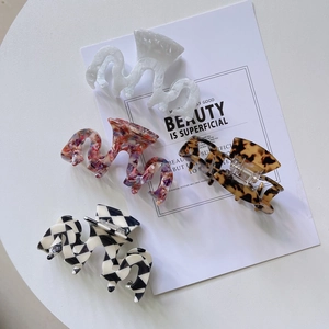 Gros plan de quatre pinces à cheveux en acétate aux motifs marbre, tie-dye et damier chic