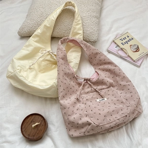 Macro shot of corduroy tote bags in yellow and floral pink on a soft bed setting