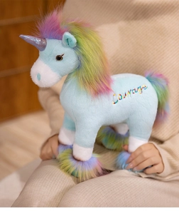 Detailed view of unicorn plush toy with colorful courage embroidery and soft rainbow mane