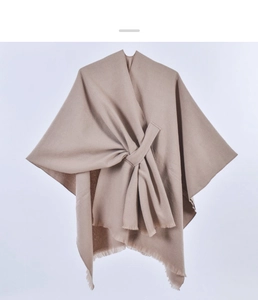 Detail of beige knitted shawl featuring a stylish knot design and soft fringe edges