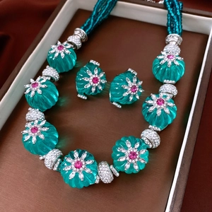 Détail d'un ensemble de bijoux en perles vertes avec pierres rouges en boîte vintage