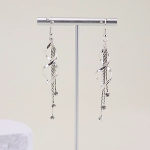 Elegant silver spiral tassel earrings with white rhinestones on a metal jewelry stand