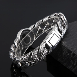 Macro detail of silver Cuban link bracelet featuring Greek key patterns and black onyx inlay