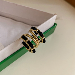 Close-up of vintage C-shape earrings with gold chain and black velvet ribbon weaving