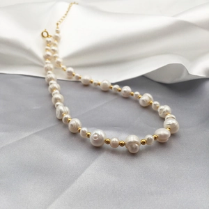 Baroque irregular freshwater pearl necklace with gold beads on elegant silk fabric background