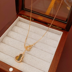 Detail of gold gourd pendant with tiger eye stone and zircons in wooden box