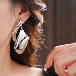 Close-up of model wearing large irregular twisted silver leaf earrings with glossy finish