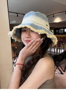 Detailed view of frayed raw edges on a gradient blue denim bucket hat worn by a model