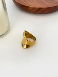 Detailed view of irregular curved stainless steel ring on a minimalist wooden tray
