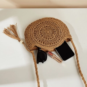 Flat lay of round straw crossbody bag showing interior capacity with holiday accessories
