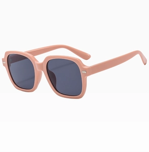 Gros plan sur des lunettes de soleil carrées rose Morandi avec détails métalliques