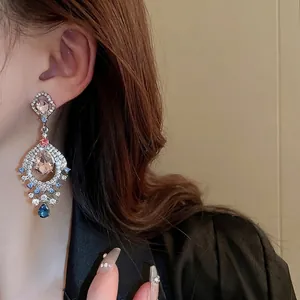 Model wearing vintage fan-shaped drop earrings with pink and blue crystal gemstones
