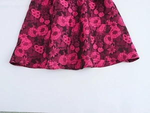 Close-up detail of dark red jacquard dress hem with pink and burgundy floral patterns
