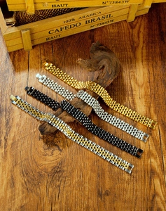 Detail view of steel watch-style bracelets in gold, silver, black, and two-tone finishes