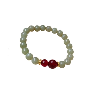 Elegant Hetian Jade beaded bracelet with red charms and gold spacers on white background
