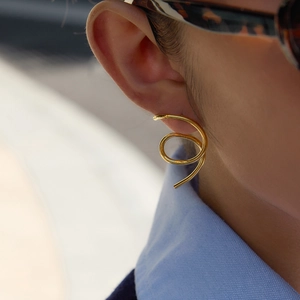 Close-up of golden 18K gold-plated irregular spiral hoop earrings on a female model