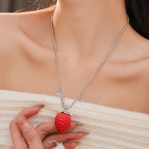Dettaglio di una collana di perline d'argento con ciondolo a fragola in resina rossa e cristalli