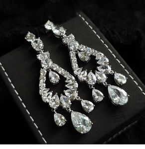 Close-up of silver drop earrings with clear cubic zirconia on a black jewelry box