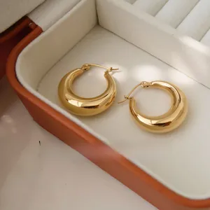 Detailed macro view of chunky golden hoop earrings in a premium velvet jewelry storage box