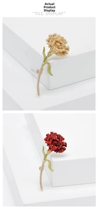 Detailed view of carnation brooches in gold and red enamel finish on white steps