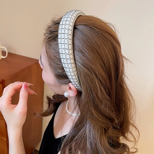 Detail of elegant beige padded headband with dark rhinestones in a lattice pattern