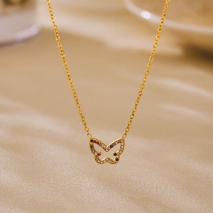 Elegant gold butterfly necklace with colorful zircon stones on minimalist beige background