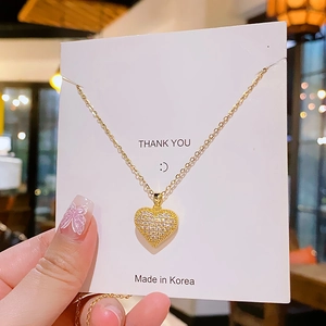 Elegant gold heart pendant necklace with shimmering cubic zirconia on white display card