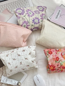 Floral print cosmetic bags in five patterns shown with laptop and accessories