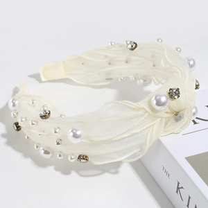 Detail of cream tulle headband with sparkling rhinestones and white pearls on a book