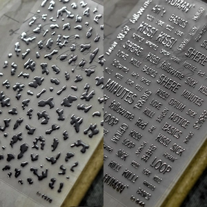 Detail view of silver laser nail stickers with 3D drop shapes and gothic text patterns