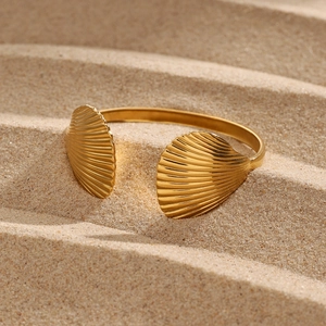 Close-up of golden stainless steel starfish seashell open bangle on sand background