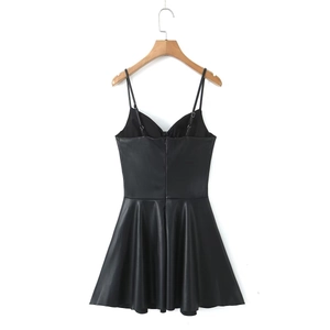 Detalle de minivestido negro de cuero sintético con tirantes finos y falda plisada
