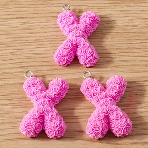 Detail of pink resin letter X charms with 3D rose relief and silver hanging loops