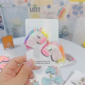 Pair of sequined unicorn hair clips with rainbow plush mane on display card