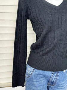 Detail of classic cable-knit texture and V-neck design on a black slim fit sweater