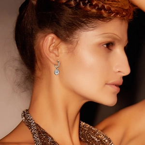 Close-up of a model wearing sparkling round-cut moissanite earrings with S925 silver hoops