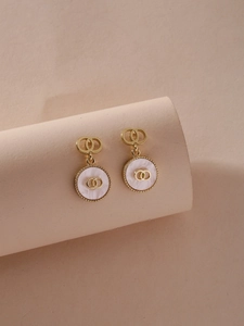Detail of gold double circle earrings with mother of pearl inlay on beige display