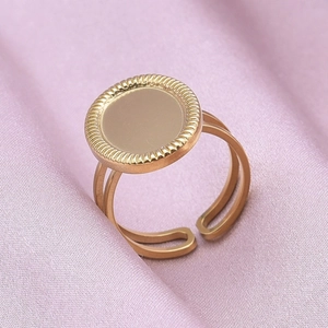 Macro detail of adjustable gold stainless steel ring with textured oval tray on purple silk