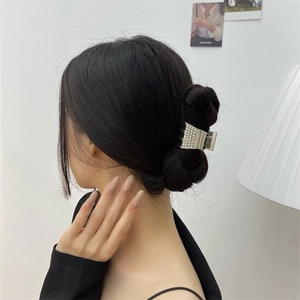 Détail macro d'une pince à cheveux argentée avec strass sur un chignon noir