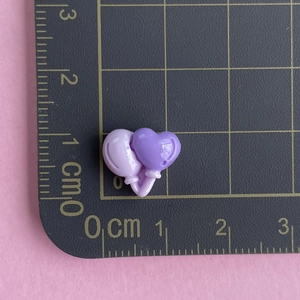 Macro shot of 1cm dual-tone purple resin heart accessory on a measuring grid scale