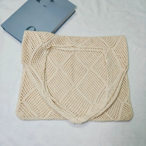Close-up of cream crochet tote bag with hollow diamond knit texture on white fabric