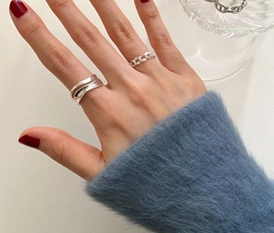Detail shot of wavy and chain-link 925 sterling silver rings worn on fingers