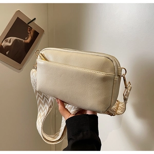 Detail of beige lychee pattern PU leather bag with wide wavy woven strap and gold hardware