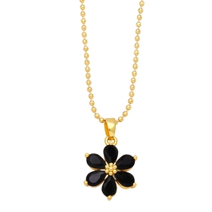 Macro detail of golden ball chain and black six-petal flower pendant with drop-shaped stones