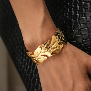 Macro shot of polished gold leaf open cuff bracelet with detailed organic texture