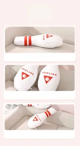 Detail of soft bowling pin plush pillow featuring classic red and white colors on a sofa