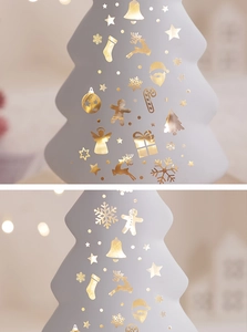 Detail of white ceramic Christmas tree with golden foil holiday icons and star patterns
