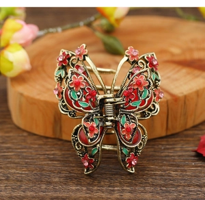 Macro detail of vintage butterfly hair claw with red enamel and pink rhinestones