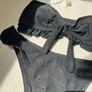 Close-up of black eyelet fabric bikini with ruffle trim and textured knot detail
